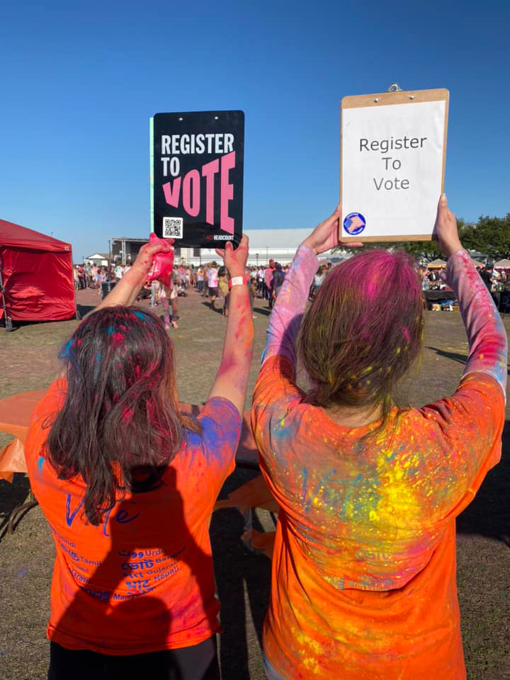 Two People Holding Up Signs Saying Register To Vote
